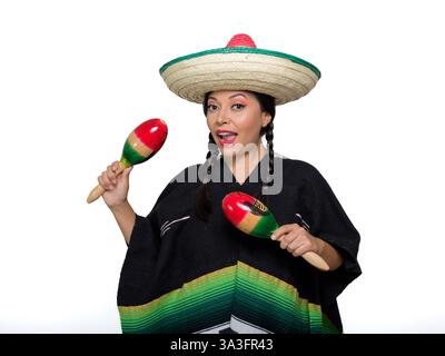 Una donna messicana sorridente che indossa un poncho colorato e un cappello gioca a maracas, isolata su sfondo bianco. Foto Stock
