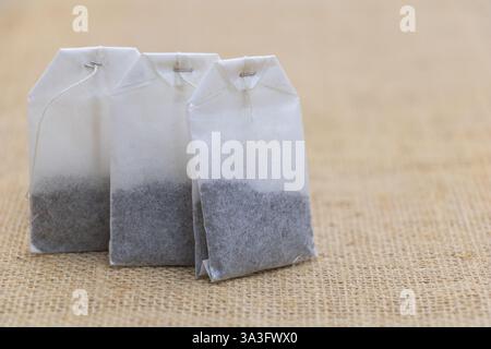 Tre bustine di tè sul tavolo, primo piano di bustine di tè di carta con caffè nero e grigio all'interno. Foto Stock