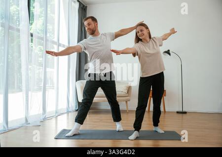 Uomo e donna fanno esercizi di yoga a casa. Foto Stock