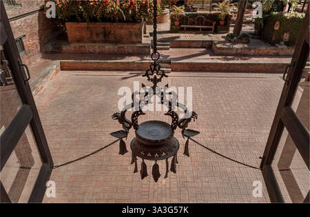Dunbar Square, Bhaktapur, Nepal - 11 febbraio 2025 - si affaccia da una finestra su un cortile con un grande portacandele tradizionale Foto Stock