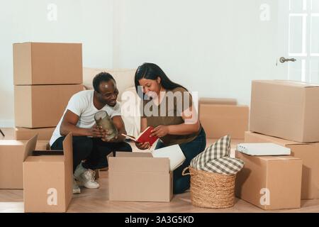 Disimballaggio dei mobili dalla scatola. La coppia afroamericana si sta trasferendo in una nuova casa. Foto Stock