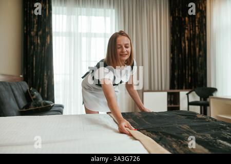Mi prendo cura del letto. Una giovane cameriera è in camera. Foto Stock