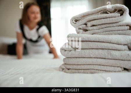 Occupato prendendosi cura del letto. Una giovane cameriera è in camera. Foto Stock