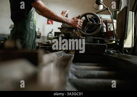 Vista laterale. Primo piano delle mani dei lavoratori che utilizzano macchinari industriali in officina. Foto Stock
