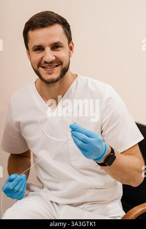 Il chirurgo vascolare è in possesso della fibra ottica laser EVLT Red per la coagulazione laser endovenosa per il trattamento di vene varicose, tromboflebite e trombosi Foto Stock