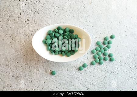 Pillole verdi spirulina o alghe clorella nel recipiente bianco. Clorella di orzo verde. Foto Stock