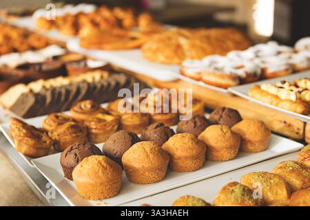 Ampia scelta di dolci appena sfornati, muffin e brioche, presentati sul tavolo del buffet in un'accogliente panetteria o caffetteria per colazione, brunch e. Foto Stock