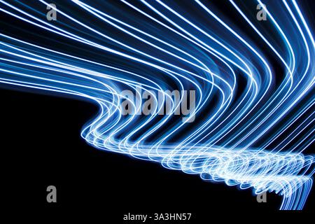 Una fotografia a lunga esposizione di una brillante luce blu elettrica con movimenti a vortice su sfondo nero Foto Stock