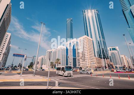 16 gennaio 2025, Abu Dhabi, Emirati Arabi Uniti: Minibus e auto che guidano su una strada trafficata, moderni grattacieli sullo sfondo Foto Stock