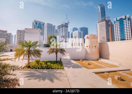 16 gennaio 2025, Abu Dhabi, Emirati Arabi Uniti: Storico forte Qasr al Hosn circondato da palme ed edifici moderni Foto Stock