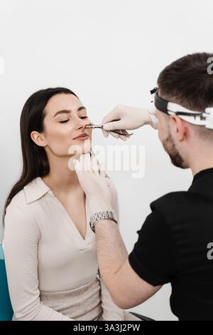 L'Otolaringologo esamina il naso della ragazza prima della procedura di endoscopia del naso. Consultazione con il medico ORL. Rinoscopia del naso della donna Foto Stock