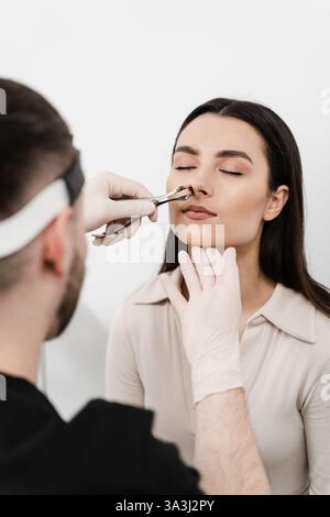 Rinoscopia del naso della donna. Consultazione con il medico ORL. L'Otolaringologo esamina il naso della ragazza prima della procedura di endoscopia del naso Foto Stock