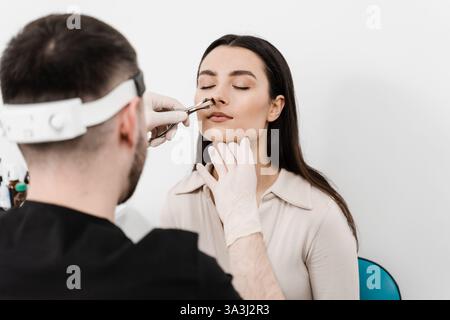 Consultazione con il medico ORL. L'Otolaringologo esamina il naso della ragazza prima della procedura di endoscopia del naso. Rinoscopia del naso della donna Foto Stock