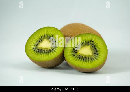 Un intero Kiwi e uno tagliato a due su sfondo bianco Foto Stock
