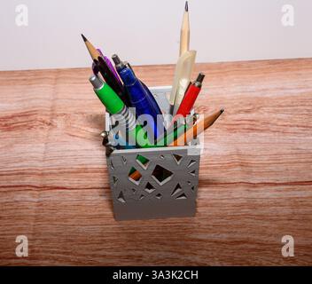 Una varietà di strumenti di scrittura sono disposti in modo ordinato in un elegante supporto, che mette in mostra un mix di colori e forme su uno sfondo chiaro Foto Stock
