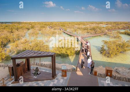 18 gennaio 2025, Abu Dhabi, Emirati Arabi Uniti: I turisti si godono una passeggiata su una passerella di legno nel bellissimo Jubail Mangrove Park, un paradiso di bellezza naturale Foto Stock