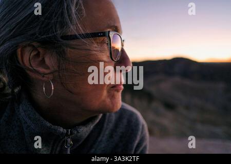 Profilo delle spalle della testa di una donna adulta anziana che guarda al tramonto, Zabriskie Point, Death Valley, California, USA Foto Stock