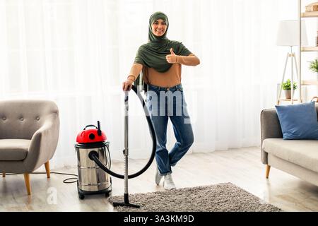 Giovane donna che ama pulire a casa mentre utilizza un aspirapolvere Foto Stock
