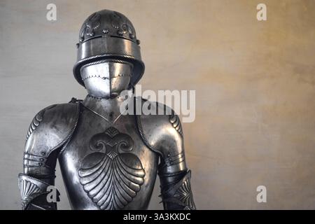 Vista frontale di un'armatura medievale lucente con dettagli e pareti bianche sullo sfondo. Foto Stock