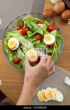 Una foto dall'alto splendidamente organizzata di un'insalata fresca ed elegante con pomodoro, lattuga e un uovo sodo, accompagnato da un bicchiere di latte e Foto Stock