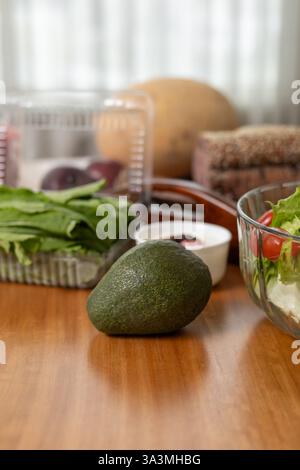 Un piatto vivace e salutare con varie verdure fresche e un avocado maturo, splendidamente disposto sul tavolo, che mostra un nutriente e sano Foto Stock