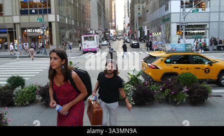 New York City, Stati Uniti - 5 settembre 2023: Manhattan Midtown Street, incrocio 6 Americas avenue. Traffico stradale, USA. Gente, pedoni sulla zebra. Taxi giallo. Bryant Park. Foto Stock