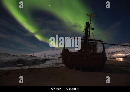 Vecchio peschereccio abbandonato sotto l'aurora boreale. Teriberka, regione di Murmansk, Russia Foto Stock