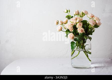 Bouquet di rose rosa in vaso di vetro su sfondo bianco. Foto Stock