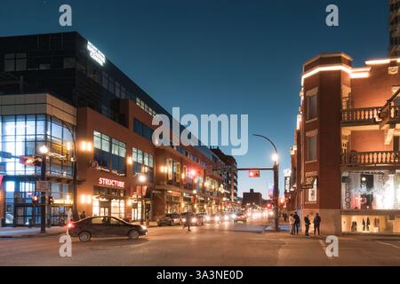 Vancouver, Canada - 11 febbraio 2023 : traffico all'incrocio della città con luci colorate, moderno e storico negozio di edifici al crepuscolo Foto Stock