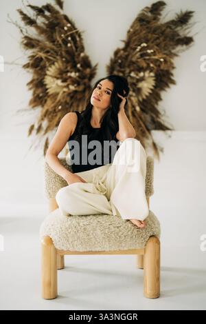 Donna seduta su una comoda sedia con sfondo in erba pampas Foto Stock