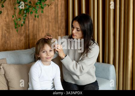Madre, controllare i capelli dei suoi figli per i pidocchi, precauzioni prevenzione dei capelli dei bambini Foto Stock