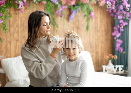Madre, controllare i capelli dei suoi figli per i pidocchi, precauzioni prevenzione dei capelli dei bambini Foto Stock