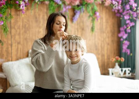 Madre, controllare i capelli dei suoi figli per i pidocchi, precauzioni prevenzione dei capelli dei bambini Foto Stock
