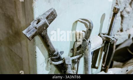 Vari utensili: Lima, cacciavite, martello, pinze, utensili da giardino sono esposti su scaffale in legno all'interno di officine o fabbriche rustiche, officina in una Foto Stock