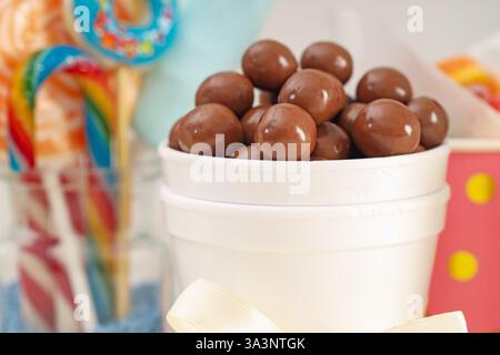 Caramelle. Dolci al cioccolato in tazza di carta su sfondo sfocato, primo piano Foto Stock
