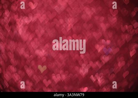 Decorazioni romantiche. Vista sfocata delle luci a forma di cuore su sfondo rosa, effetto bokeh Foto Stock