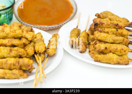 Satay di maiale con salsa di arachidi servito con sottaceti che sono fette di cetriolo e cipolle nell'aceto al mercato tailandese di Street food o al ristorante di Bangkok T. Foto Stock