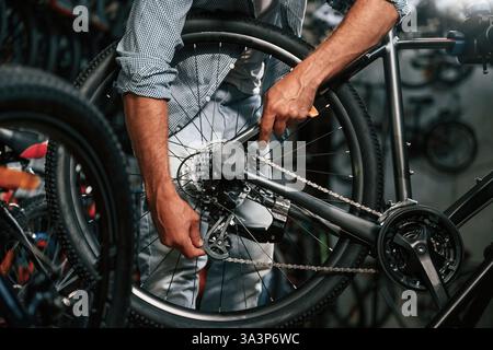 Vista ravvicinata delle mani dell'uomo che sta riparando la bicicletta. Foto Stock
