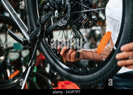 Vista ravvicinata delle mani dell'uomo che sta riparando la bicicletta. Foto Stock
