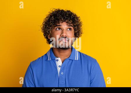 Ritratto di un giovane uomo alla moda su un vivace sfondo giallo, vestito con una polo blu alla moda Foto Stock