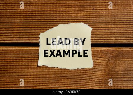 Dare l'esempio di un messaggio scritto su carta strappata su sfondo di legno. Guida concettuale con simbolo di esempio. Copia spazio. Foto Stock