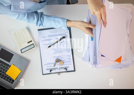 L'uomo d'affari che cerca importanti documenti contrattuali dalla pila di documenti sul tavolo conferma l'accordo che ha firmato con un investitore. Uomo d'affari chec Foto Stock