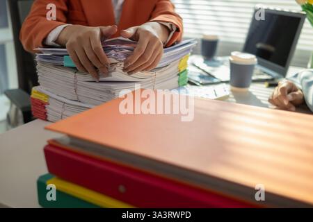 L'uomo d'affari che cerca importanti documenti contrattuali dalla pila di documenti sul tavolo conferma l'accordo che ha firmato con un investitore. Uomo d'affari chec Foto Stock