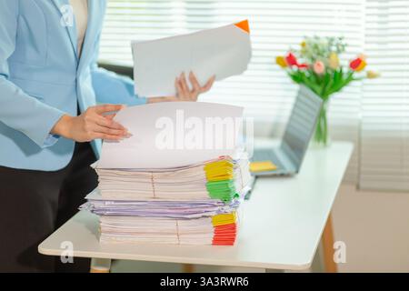 L'uomo d'affari che cerca importanti documenti contrattuali dalla pila di documenti sul tavolo conferma l'accordo che ha firmato con un investitore. Uomo d'affari chec Foto Stock