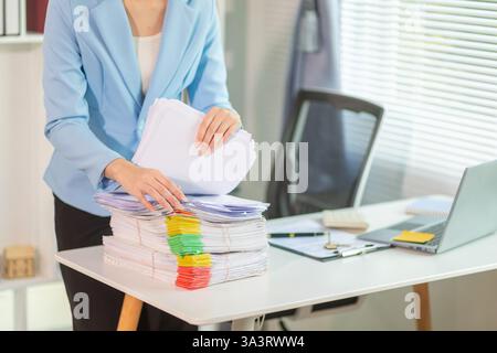 L'uomo d'affari che cerca importanti documenti contrattuali dalla pila di documenti sul tavolo conferma l'accordo che ha firmato con un investitore. Uomo d'affari chec Foto Stock