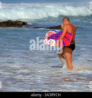 Uomo con bodyboard colorato che cammina in mare, spiaggia di surf Piedra Playa, El Cotillo, Fuerteventura, Isole Canarie, Spagna, Europa, UE Foto Stock