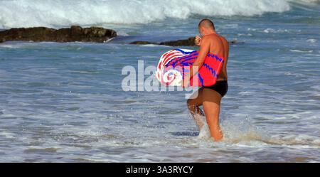 Uomo con bodyboard colorato che cammina in mare, spiaggia di surf Piedra Playa, El Cotillo, Fuerteventura, Isole Canarie, Spagna, Europa, UE Foto Stock