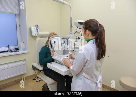 Una donna nell'ufficio di un oftalmologo controlla la sua visione su una macchina. Foto di alta qualità Foto Stock