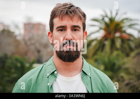 Ritratto di un giovane con la barba che guarda direttamente la fotocamera, trasudando fiducia e forza. La sua intensa espressione affascina lo spettatore, Re Foto Stock
