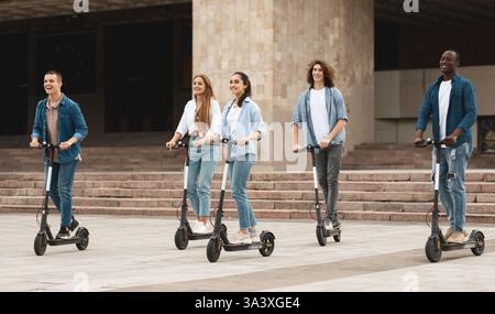 Cinque amici che hanno una piacevole corsa su scooter a calcio motorizzati Foto Stock